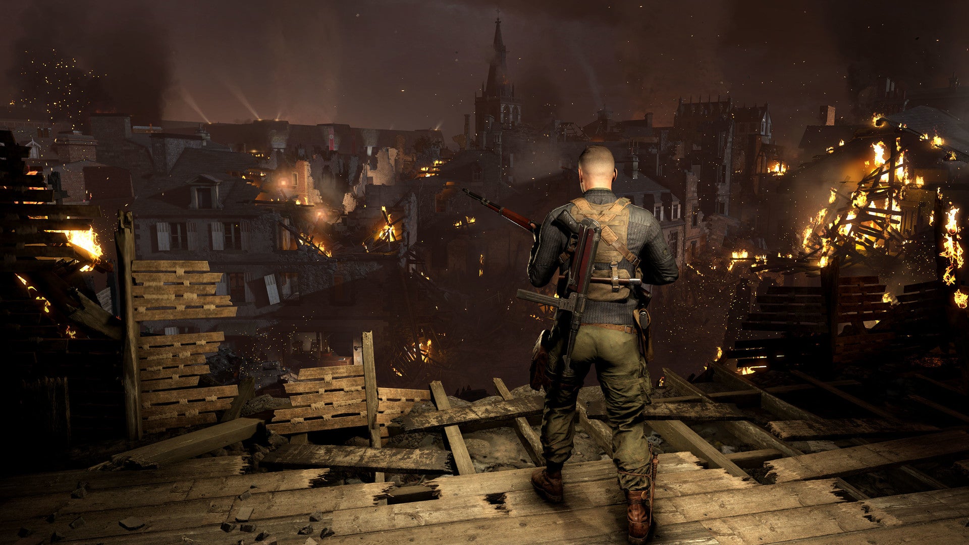 2022 best games Sniper Elite 5 - at night, dressed in black, the sniper walks out towards the edge of a platform overlooking a burning city