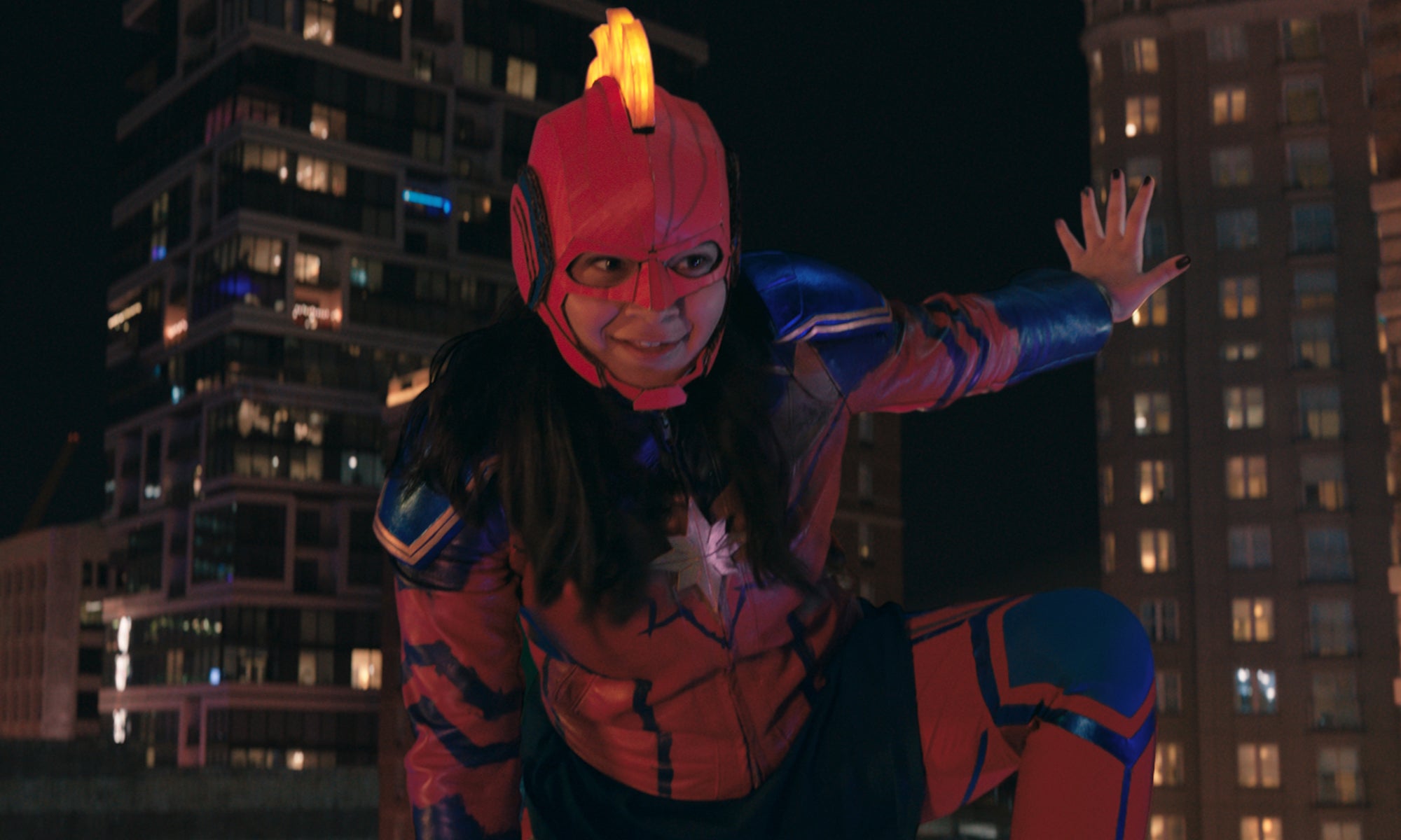 A young woman (Kamala Khan) on a rooftop in costume as Captain Marvel