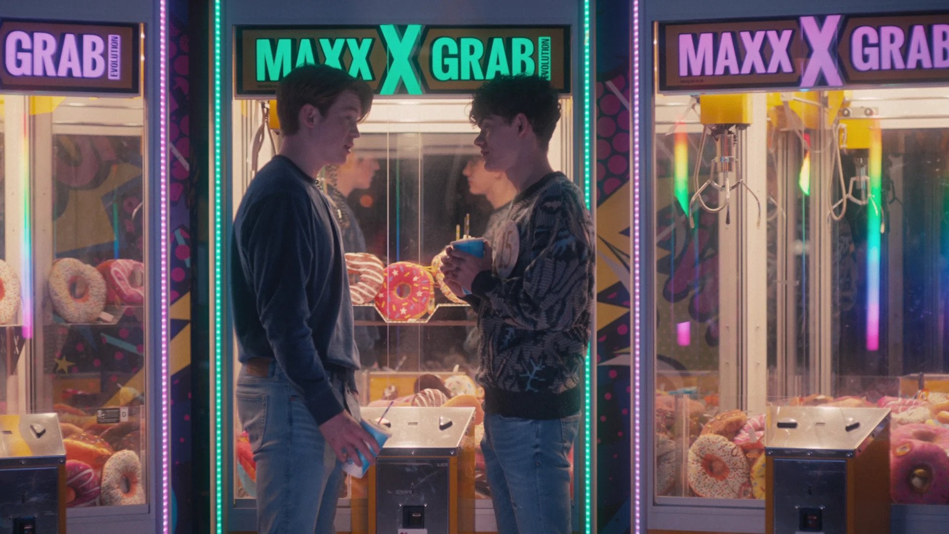 Charlie and Nick standing in front of claw machines in arcade