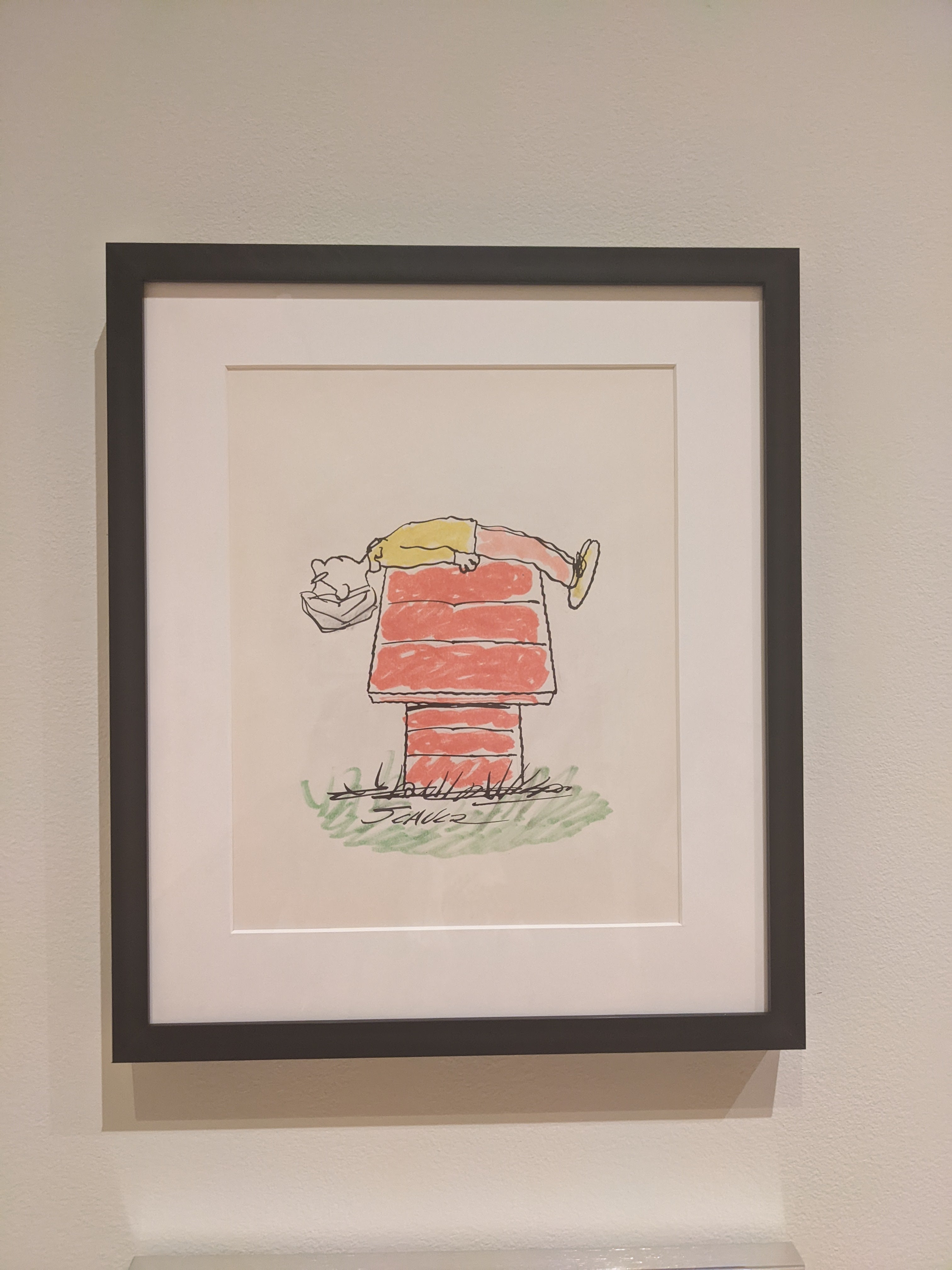 Photograph of a framed self portrait of Charles M. Schultz on Snoopy's doghouse
