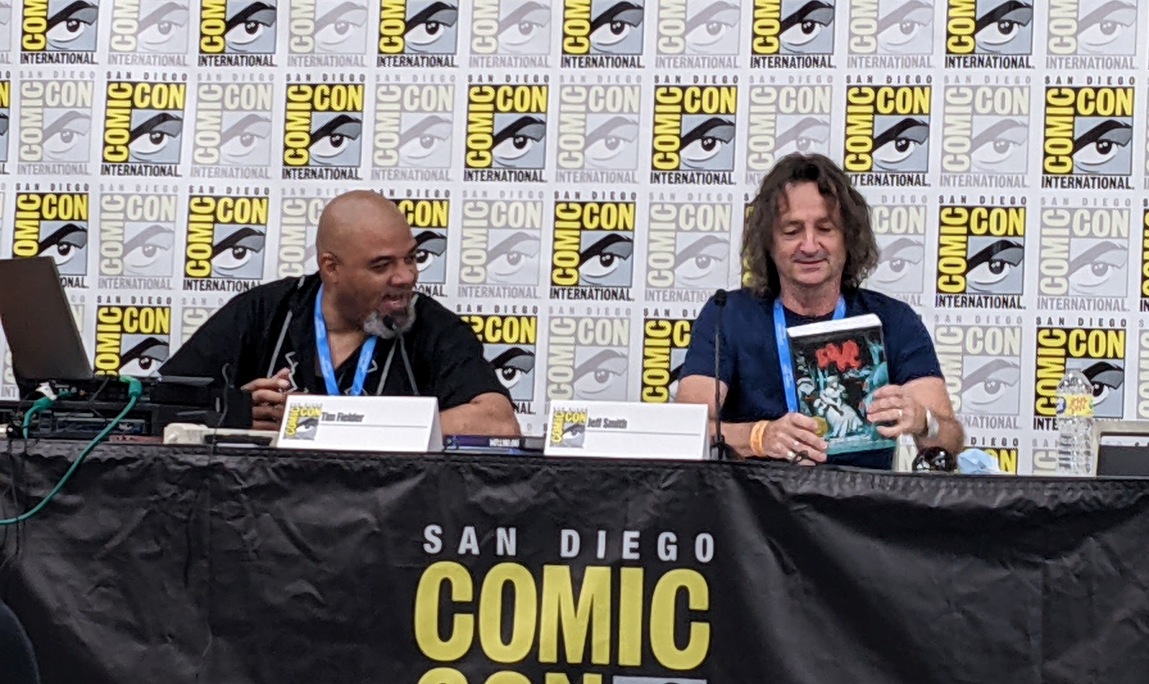 Tim Fielder and Jeff Smith sit at panel in front of SDCC banner