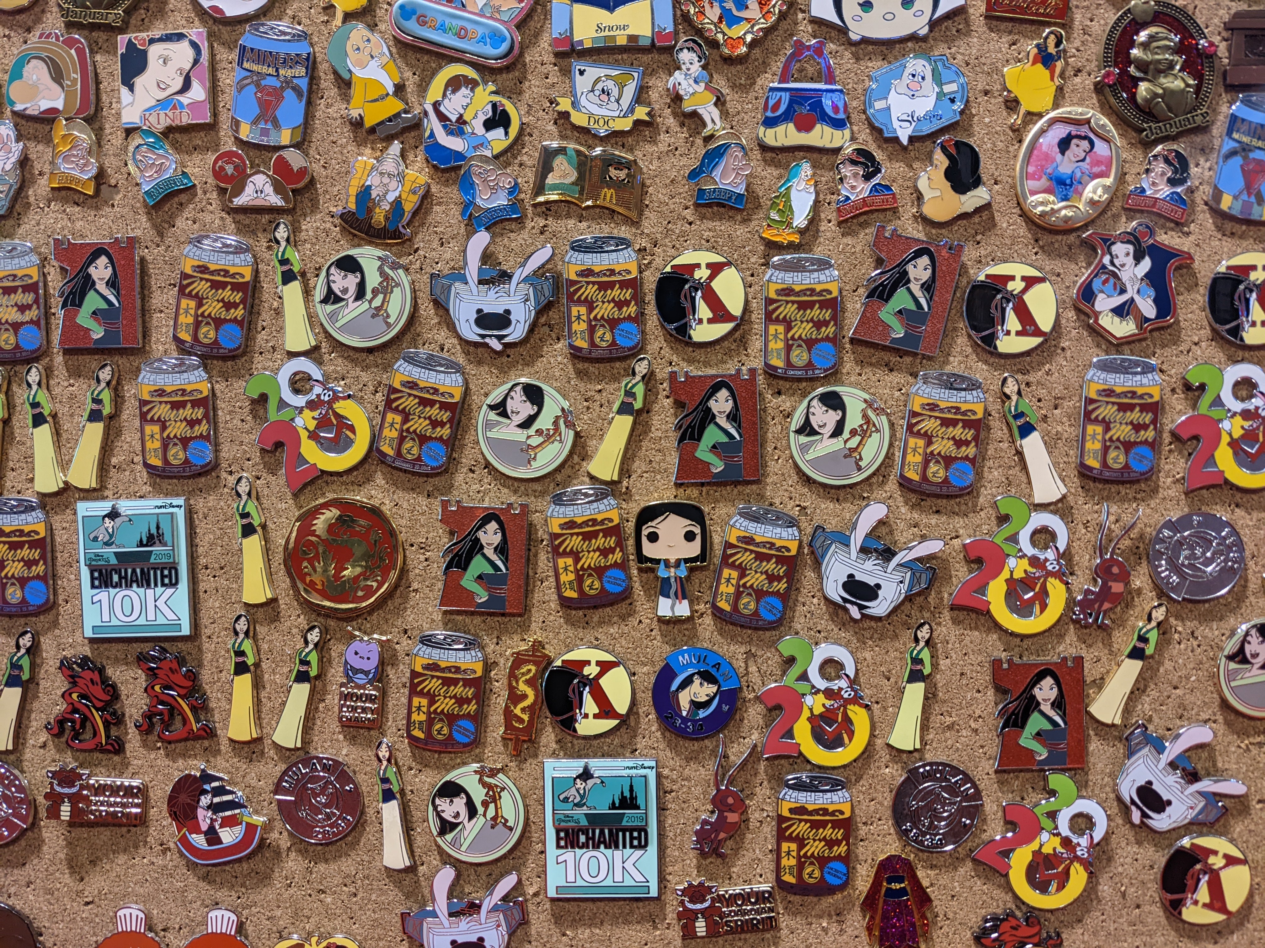 An assortment of Mulan pins on corkboard in a booth at D23