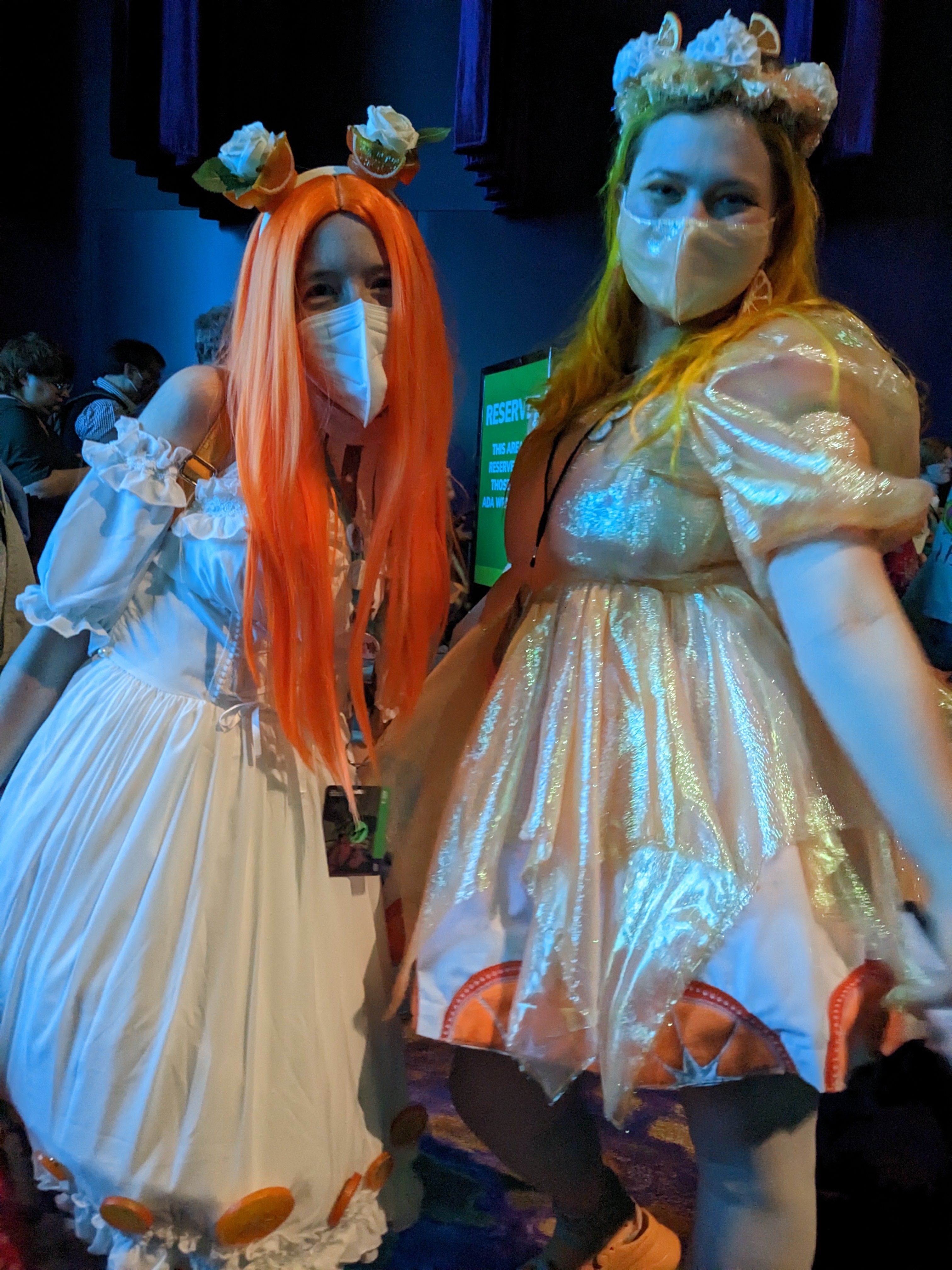 Two people wearing orange and white dresses