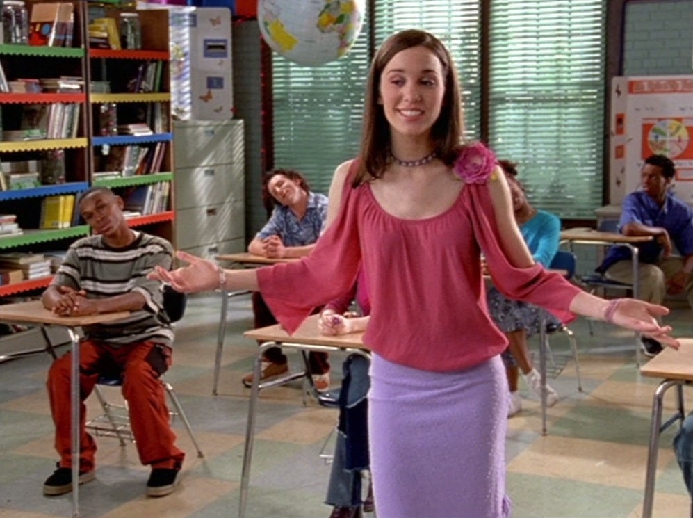 Chrissy Carlson Romano as Ren wearing pink and purple, presenting on the moon