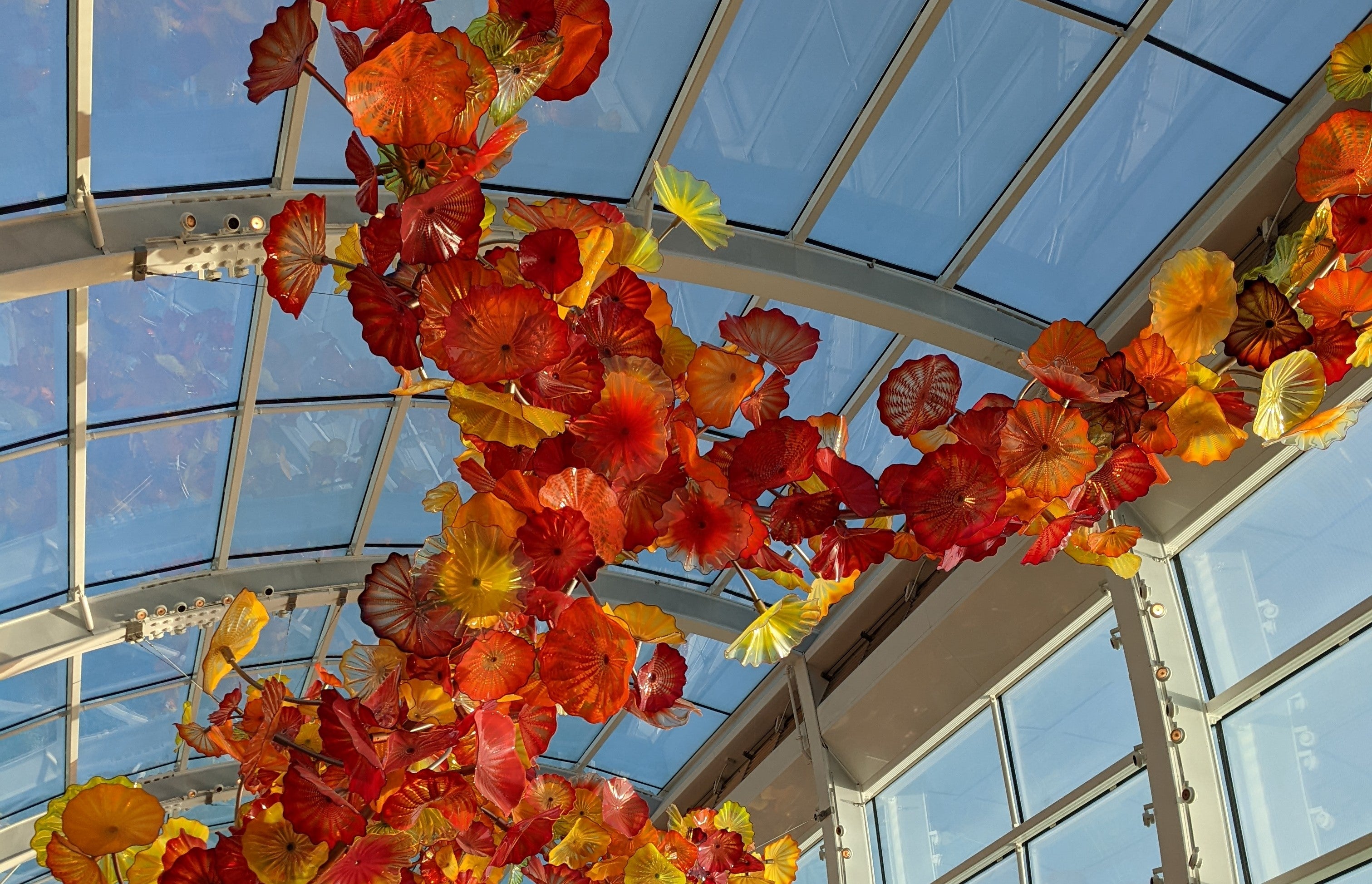 Photograph of a glass sculpture in a glass building, red, yellow, orange disks connected