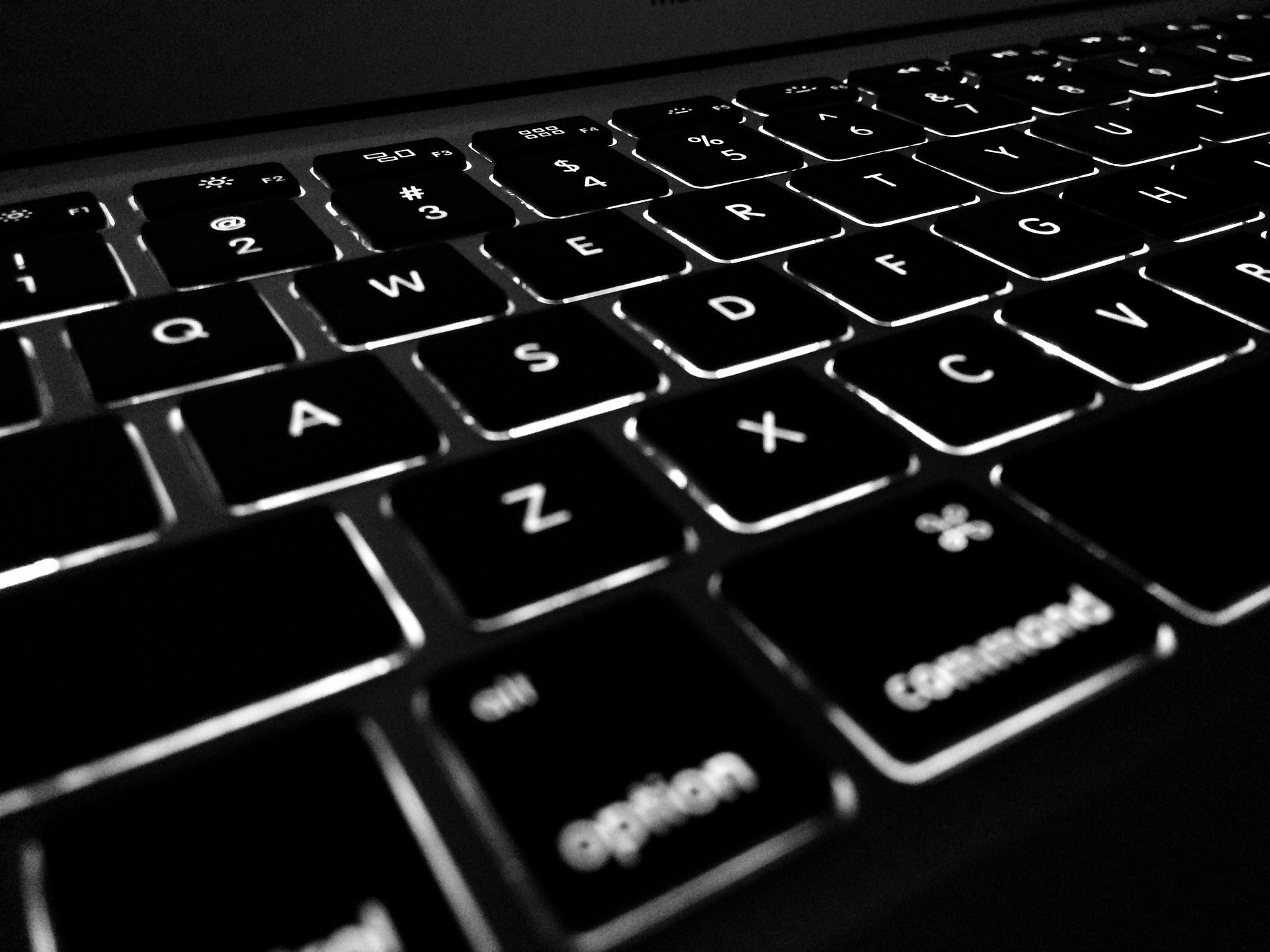 Closeup photograph of a backlit black laptop keyboard