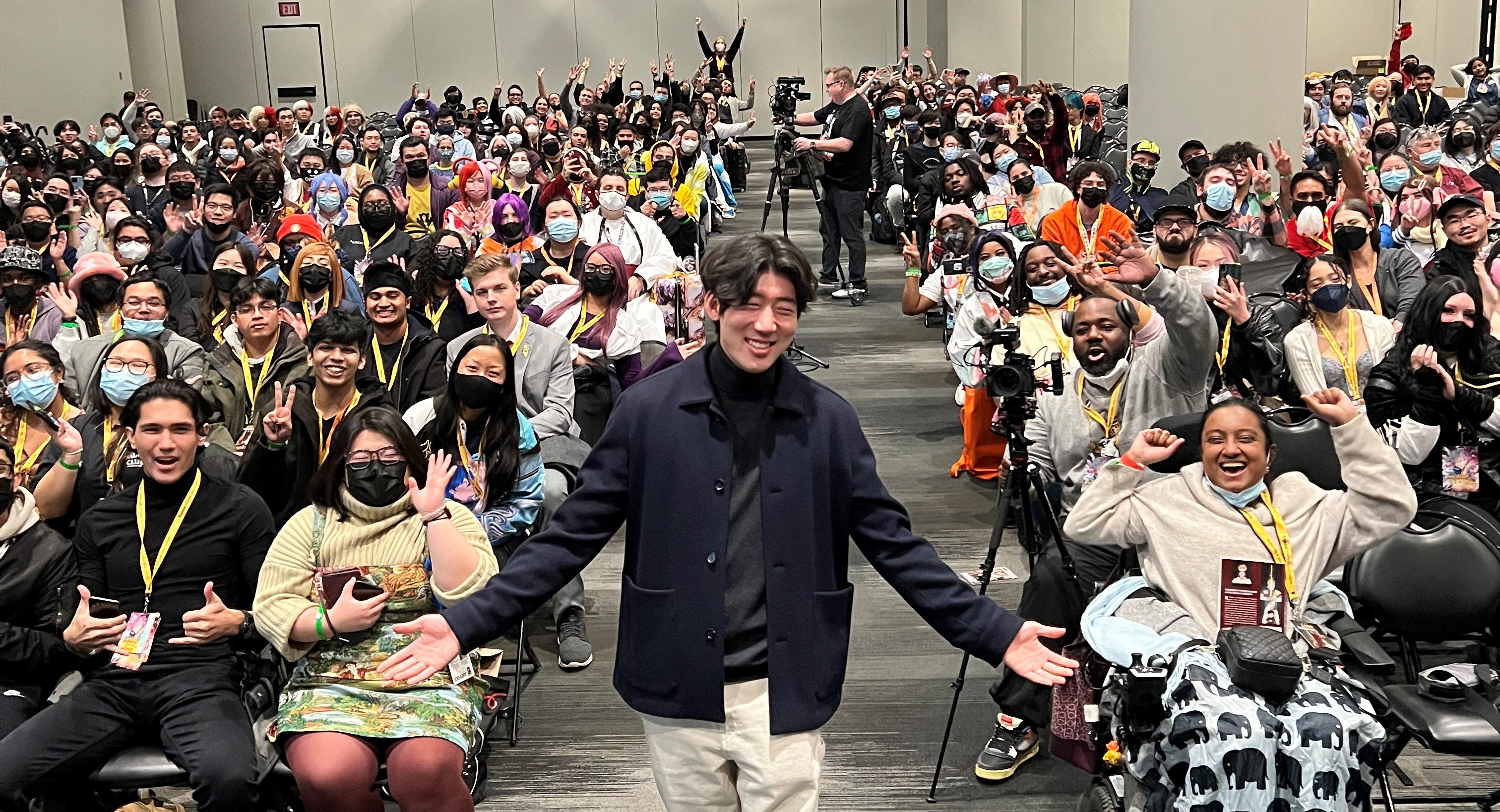 Cropped image of TurtleME aka Brandon Lee standing with his hands out in front of a packed panel at Anime NYC
