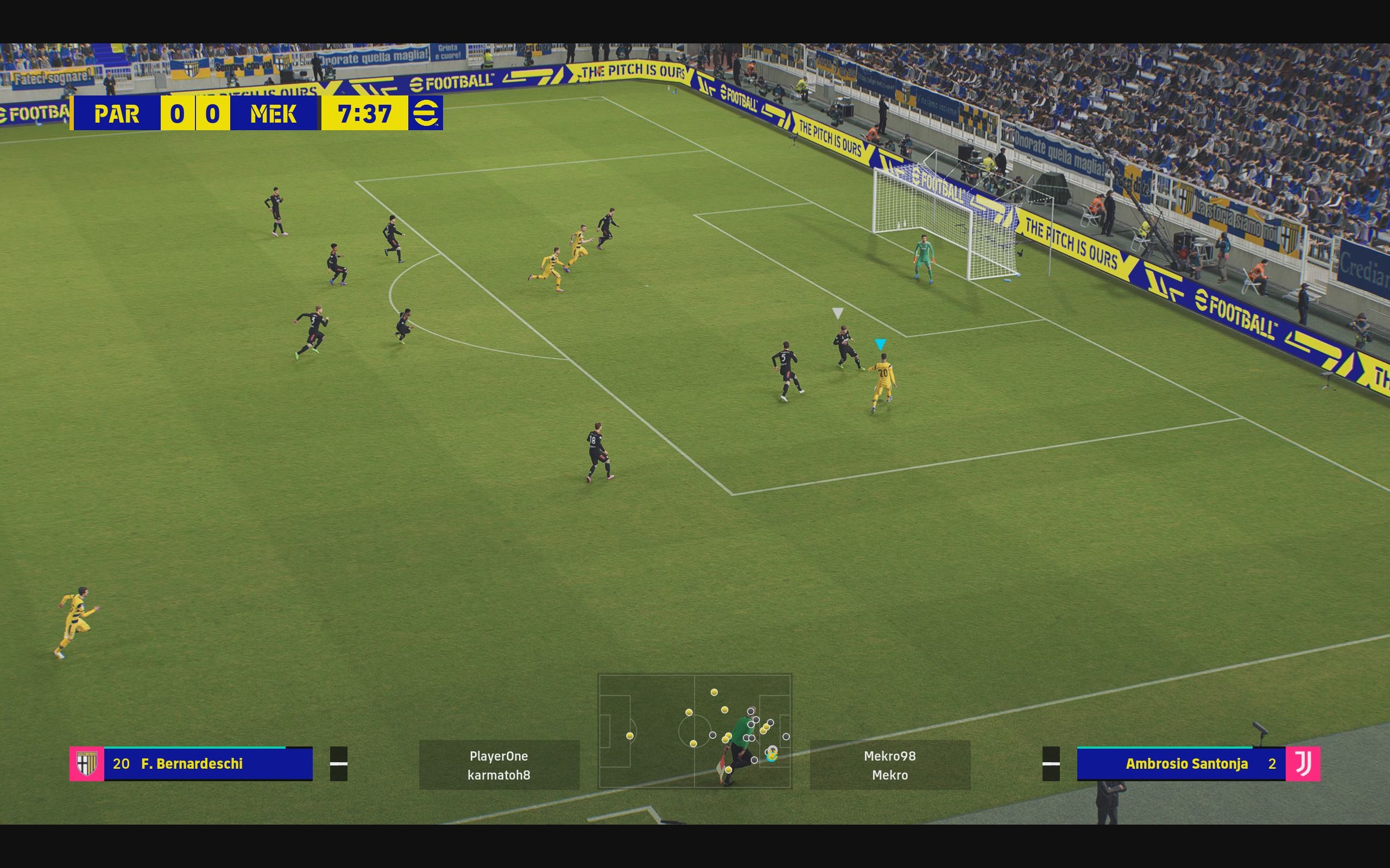 eFootball review: Screenshot from a match of an all-yellow team entering the opposition's penalty area while attacking an all-black team.