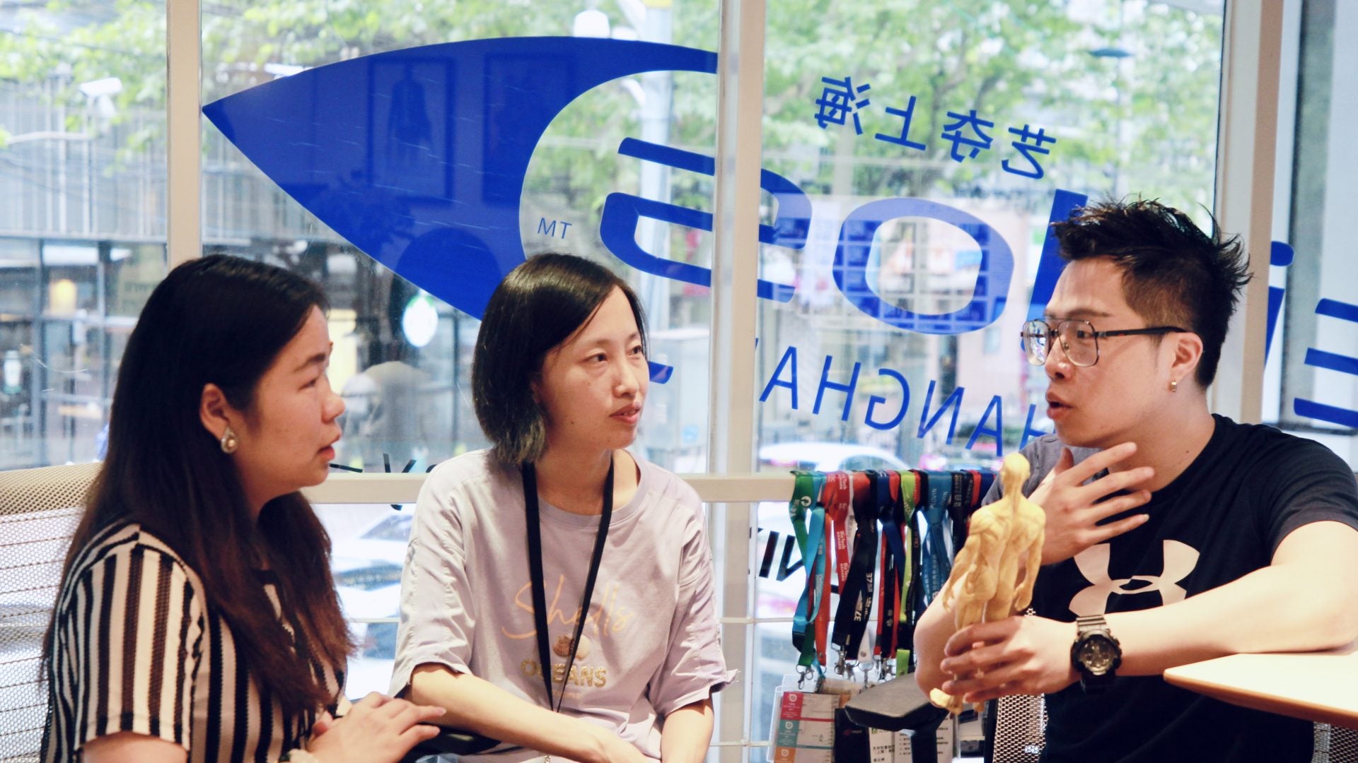 People talking in front of a window with the Eidos Shanghai logo on it
