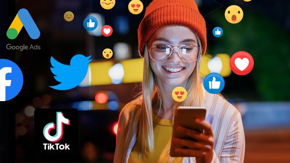 A smiling woman on her cell phone surrounded by emojis and social platform logos