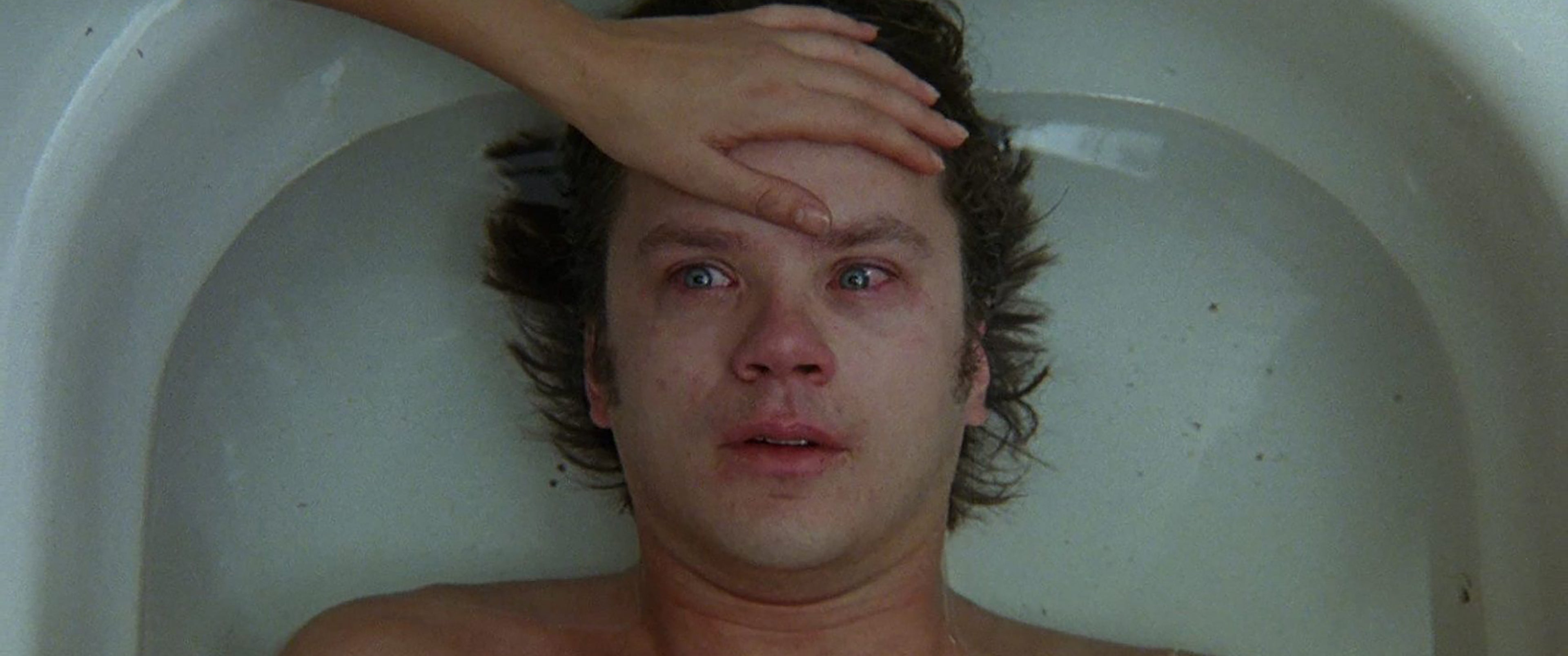 Still image from Jacob's Ladder. Tim Robbins lays in bath, as someone sets their hand on his forehead