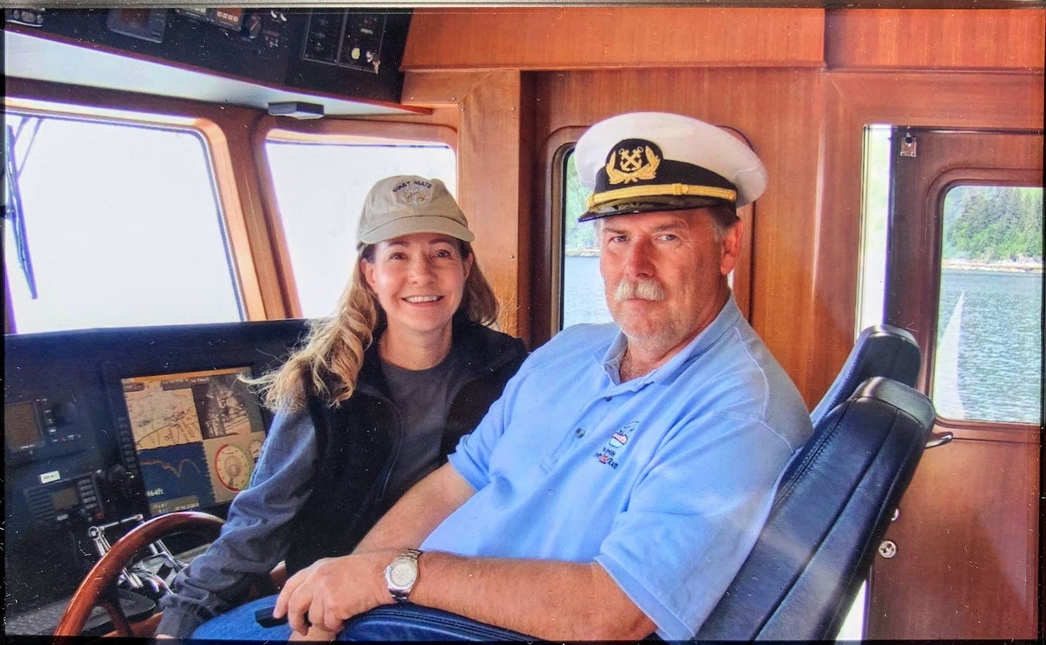 Ken and Roberta Williams inside a wooden cockpit of a boat. Ken is looking particularly fetching in his captain's hat and moustache.