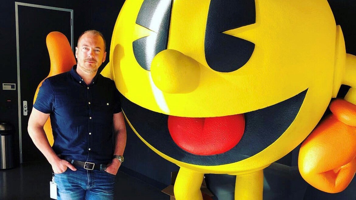 UK games publishing legend Lee Kirton stands next to a giant statue of Pac-Man. They are the best of friends.