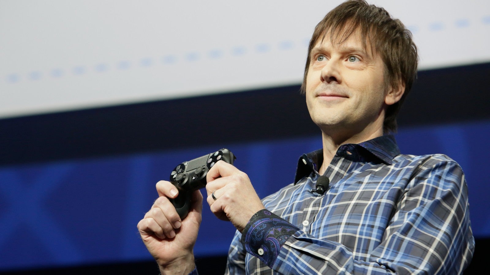 Mark Cerny holds up a DualShock 4 controller during Sony's PS4 reveal event in February of 2013