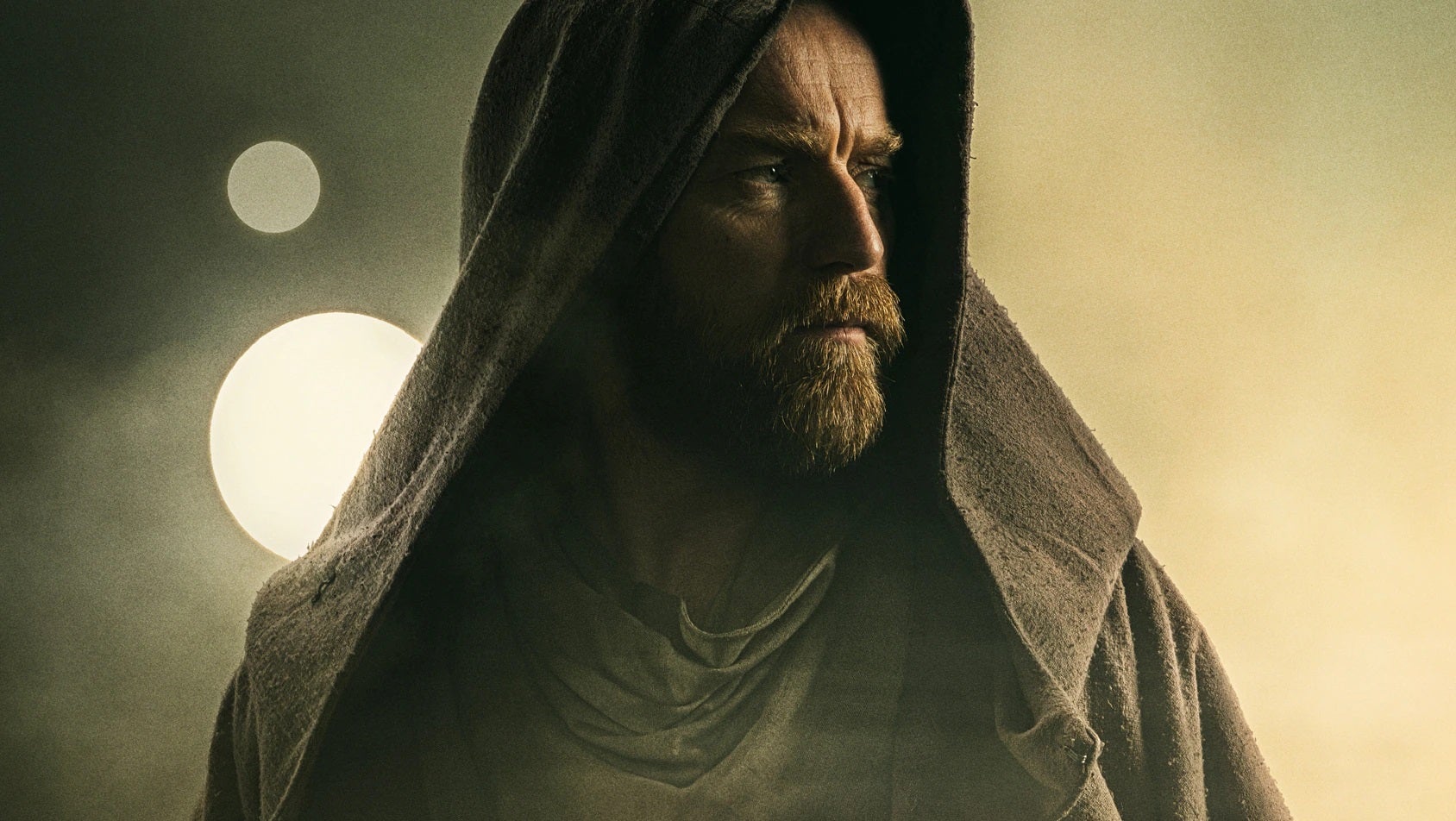 Obi-Wan Kenobi wearing Jedi robes with the two suns of Tattooine behind him