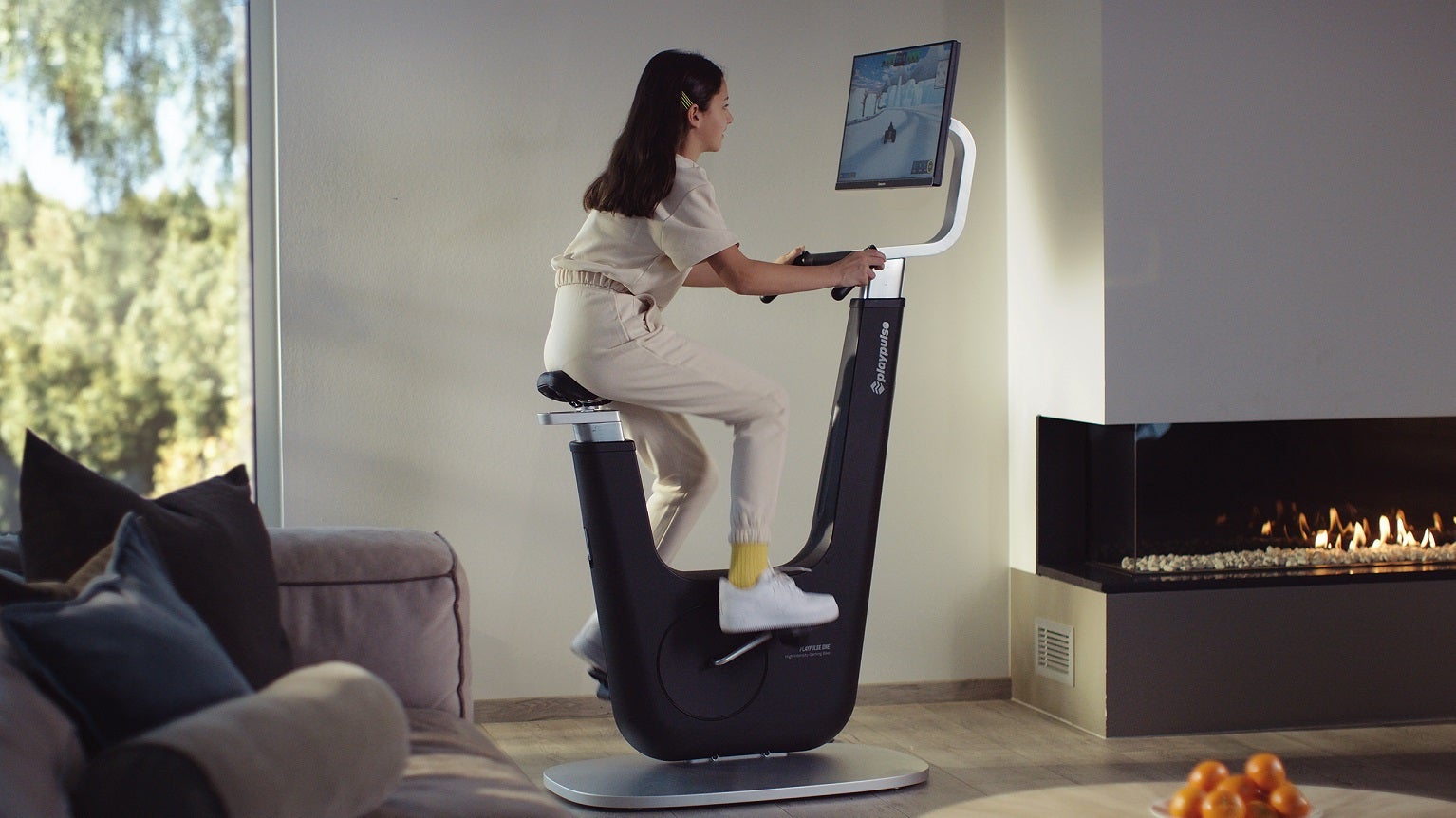 A girl rides on a PlayPulse bike while playing a game on its built-in screen