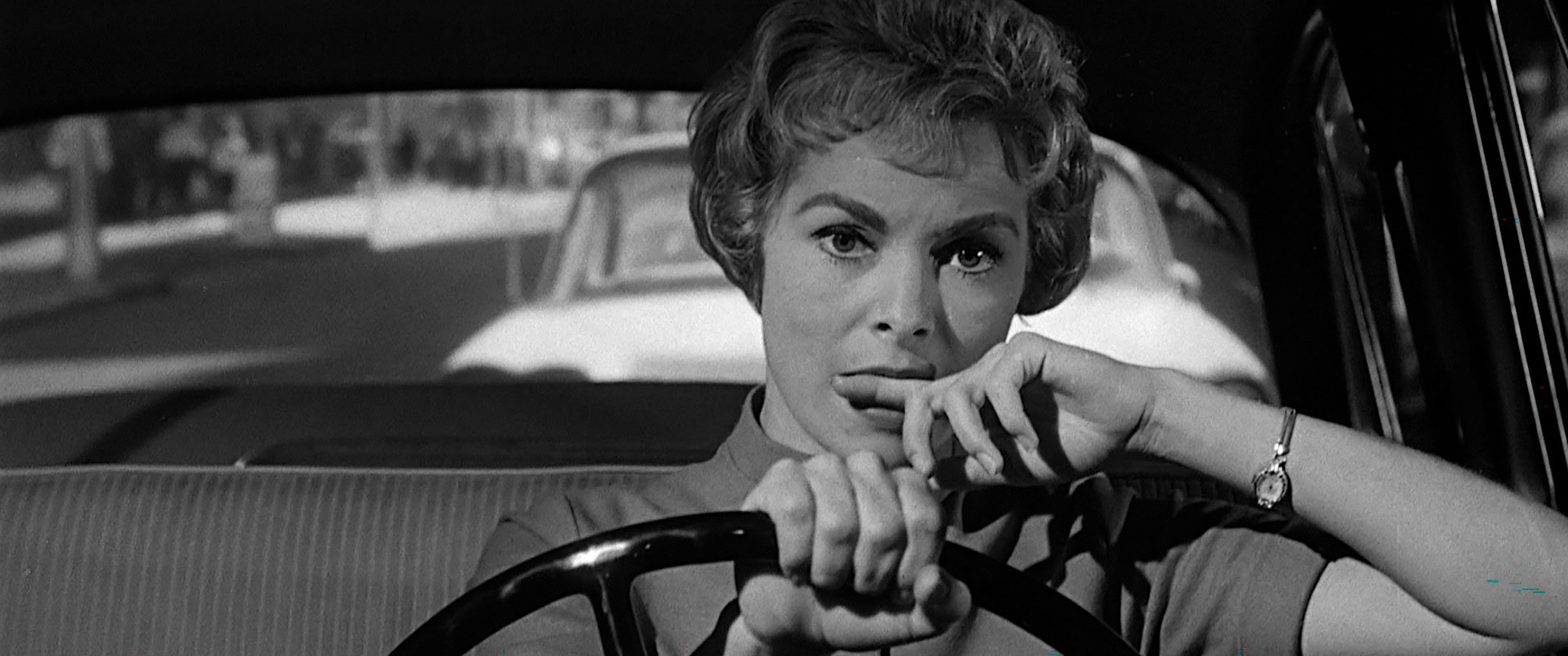 Still image from Psycho. Janet Leigh bites her finger as she drives, with a worried expression on her face.