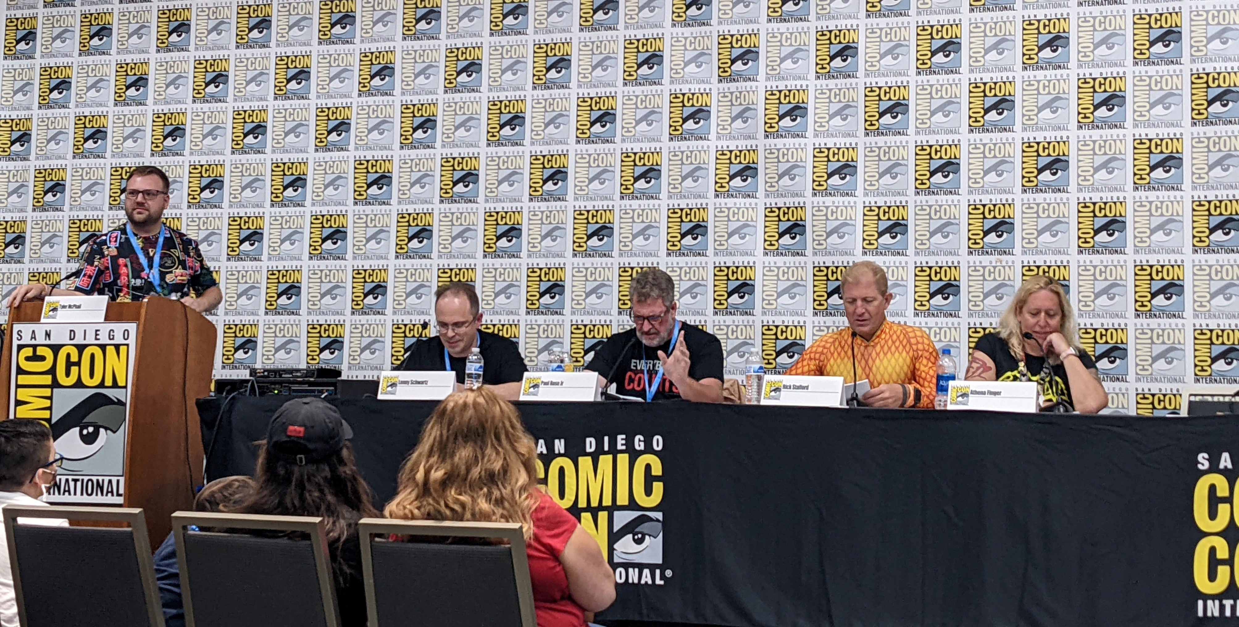 Photograph of panel reading in front of SDCC banner