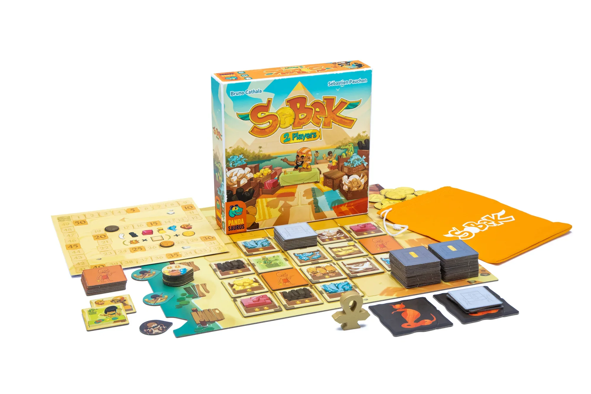 A wide shot of the Sobek: 2 Player board game, featuring the box, playing board,  icons, cards and so on. It's an Egyptian-themed game so the colours are sandy yellow.