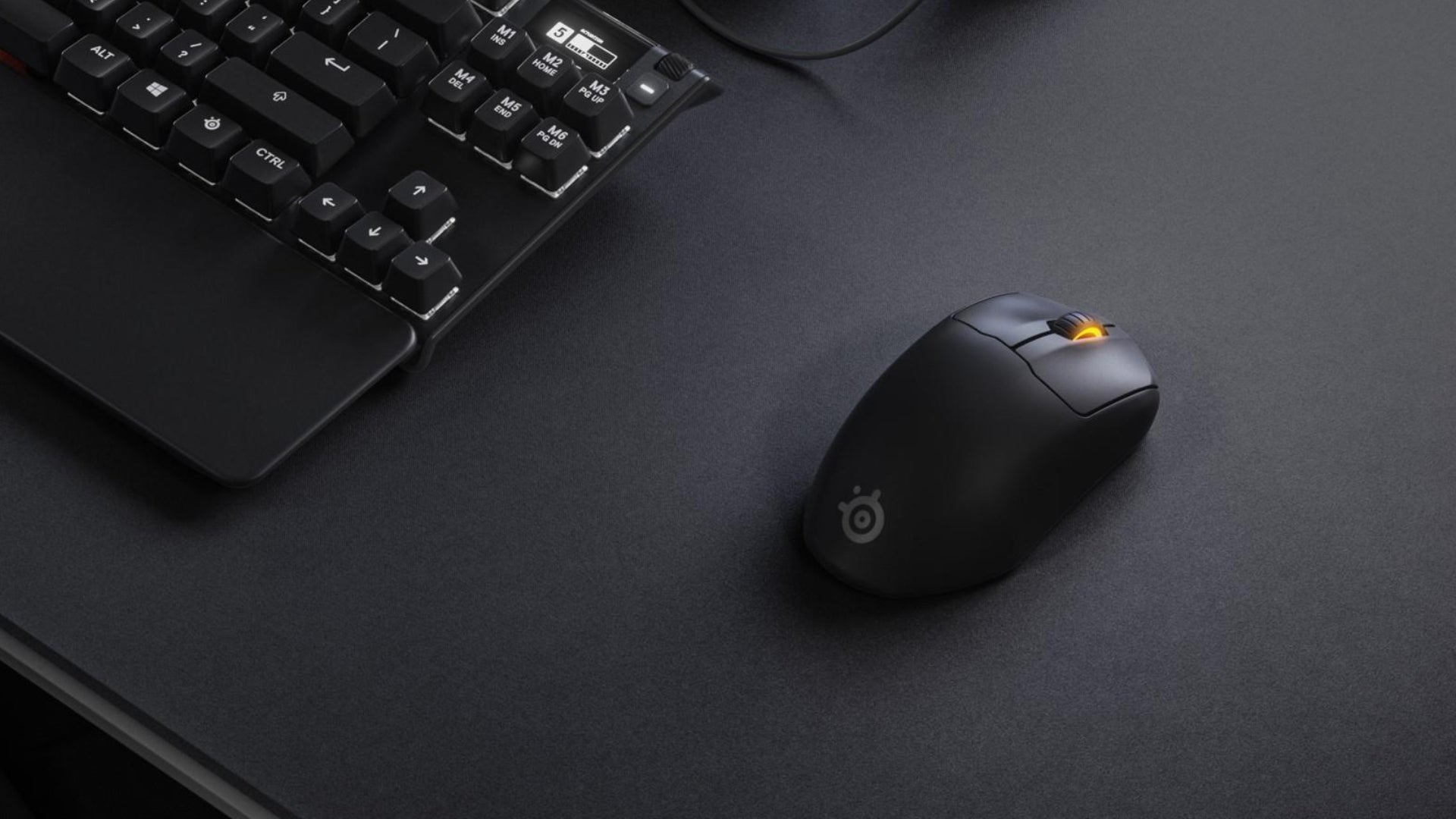 The SteelSeries Prime Mini gaming mouse on a desk next to a keyboard.