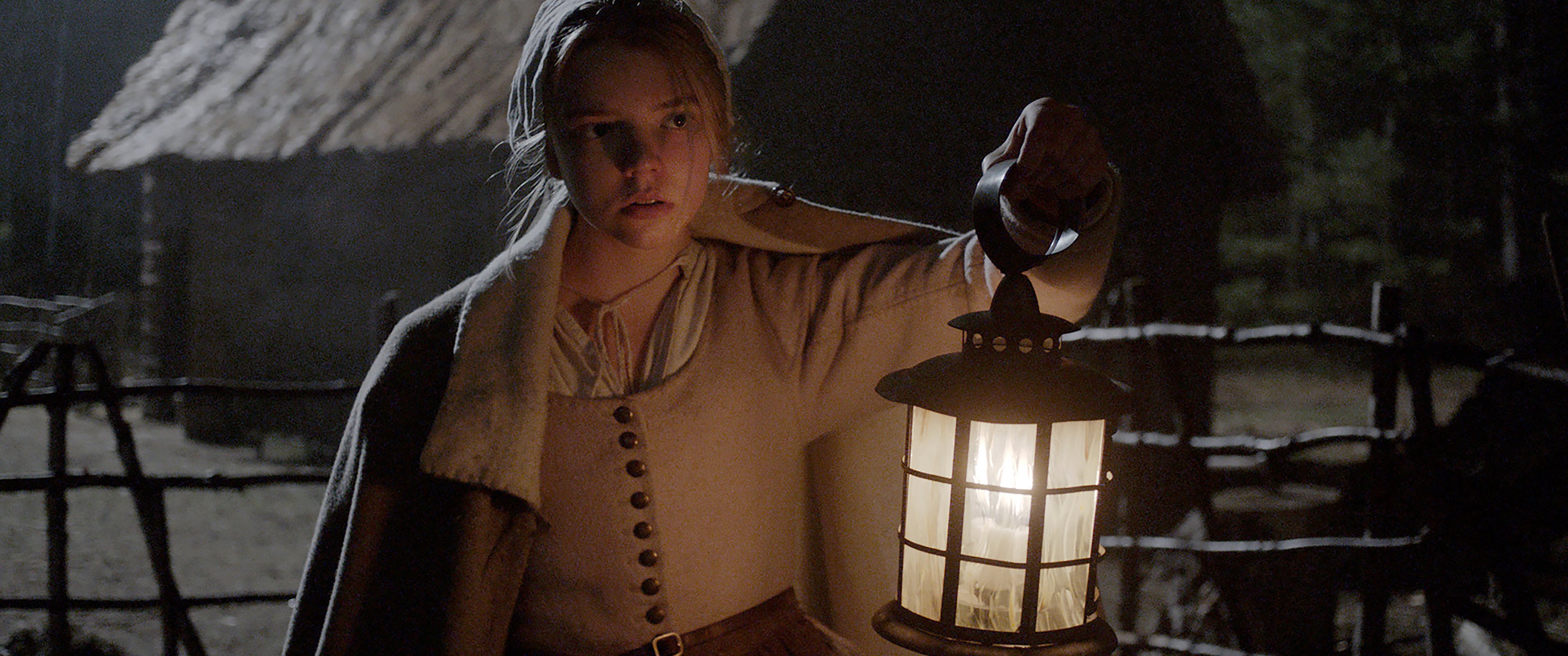 Still image from The Witch. Anya Taylor Joy carries a lantern in the dark.